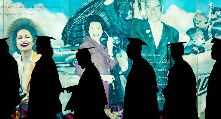LBJ students line up to attend the 2019 commencement ceremony in front of the lighted LBJ mural wall